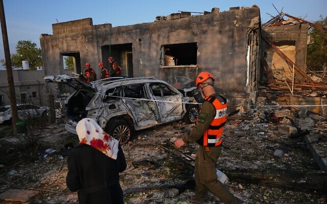 Des habitants et des officiers du Commandement du Front intérieur israélien inspectent une maison détruite par un tir de missile iranien dans la ville de Zarzir, dans le nord du pays, le 13 mars 2026. (Crédit : AP Photo/Ariel Schalit)