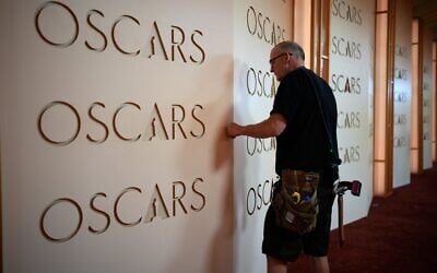 Un technicien installant une toile de fond le long du tapis rouge en prévision de la cérémonie des Oscars, à Los Angeles, en Californie, diffusée le 14 mars 2026. (Crédit : John Locher/AP Photo)