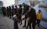 Des terroristes armés du Hamas et du Jihad islamique palestinien saluant les fidèles rassemblés pour la prière de l'Aïd al-Fitr, à Gaza-City, le 20 mars 2026. (Crédit : Abdel Kareem Hana/AP)