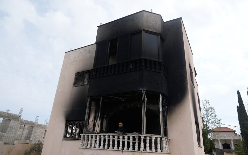 Un Palestinien se tenant sur le balcon d'une maison incendiée à la suite des violences perpétrées par des résidents d'implantations, dans les villages voisins de la région de Naplouse la veille au soir, dans le village de Deir al-Hatab, en Cisjordanie, le 23 mars 2026. (Crédit : Majdi Mohammed/AP)