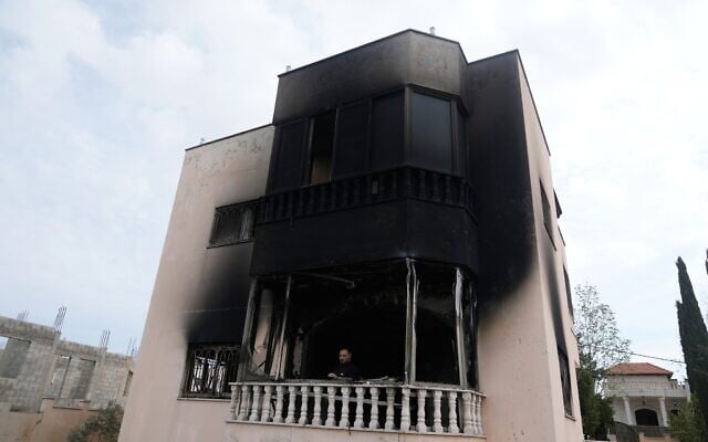 Un Palestinien se tenant sur le balcon d'une maison incendiée à la suite des violences perpétrées par des résidents d'implantations, dans les villages voisins de la région de Naplouse la veille au soir, dans le village de Deir al-Hatab, en Cisjordanie, le 23 mars 2026. (Crédit : Majdi Mohammed/AP)