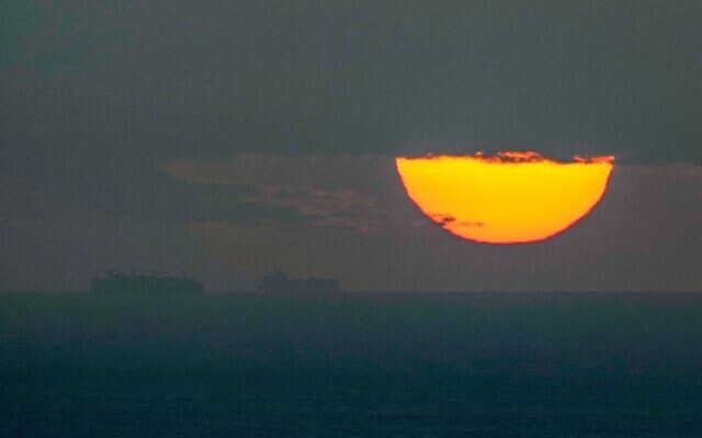 Des navires traversant le golfe Persique en direction du détroit d’Ormuz alors que le soleil se couche aux Émirats arabes unis, le 23 mars 2026. (Crédit : AP)