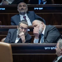 Le chef du parti Shas, le député Aryeh Deri (à droite) s'entretenant avec le numéro 2 du parti Yahadout HaTorah, le député Moshe Gafni, lors d'une séance plénière de la Knesset, à Jérusalem, le 10 février 2025. (Crédit : Yonatan Sindel/Flash90)