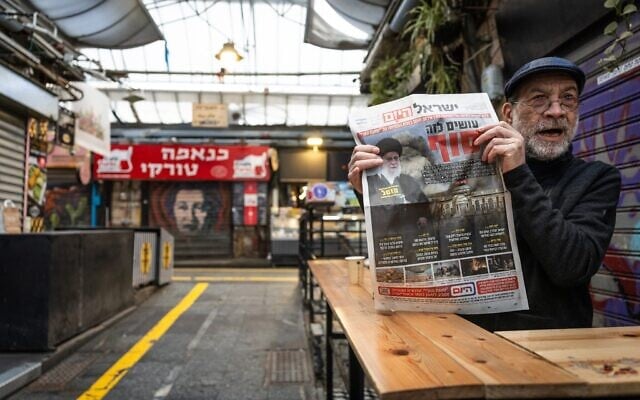 Un homme tient un exemplaire du quotidien hébreu Israel Hayom au marché Mahane Yehuda, à Jérusalem, dont la une est consacrée au guide suprême iranien, l'ayatollah Ali Khamenei, tué lors d'une frappe militaire israélienne, le 1er mars 2026. (Crédit : Yonatan Sindel/Flash90)