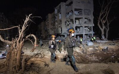 Les forces de sécurité et de secours israéliennes sur les lieux où un missile tiré depuis l'Iran en direction d'Israël a endommagé des immeubles, dans la ville d'Arad, dans le sud du pays, le 22 mars 2026. (Crédit : Chaïm Goldberg/Flash90)