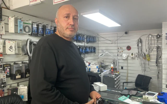 L'avocat Samy Faisal, qui ne peut pas représenter ses clients car les tribunaux ne traitent aucune affaire avant le 14 avril, achète un téléphone portable pour sa mère dans la ville de Haïfa, au nord du pays, le 24 mars 2026. (Crédit : Sue Surkes/Times of Israel)