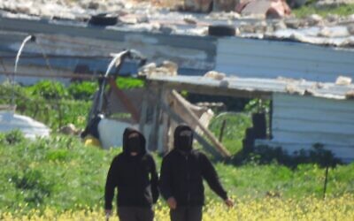 Des résidents d'implantations extrémistes menacent des militants palestiniens bédouins ainsi que des militants israéliens des droits de l'homme dans les ruines du hameau bédouin palestinien de Khallet a-Sidra, des environs de Mukhmas, le 8 mars 2026 (Crédit : Torat Tzedek)