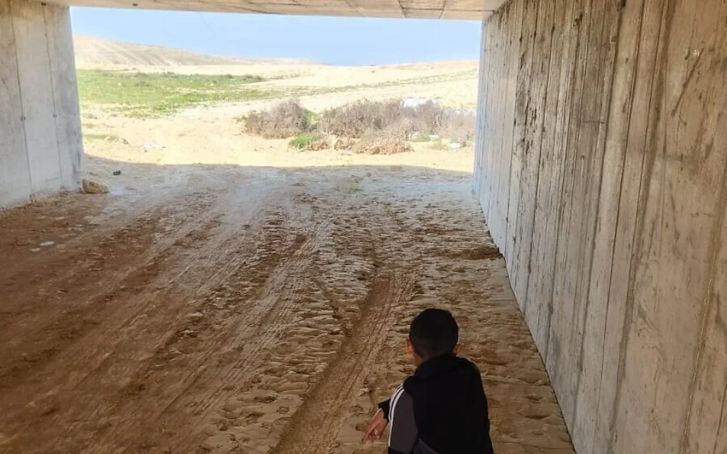 Un garçon bédouin s’abrite d’un missile iranien sous un tunnel en béton dans le village de Wadi NaAm, en mars 2026. (Crédit : Neguev Coexistence Forum)