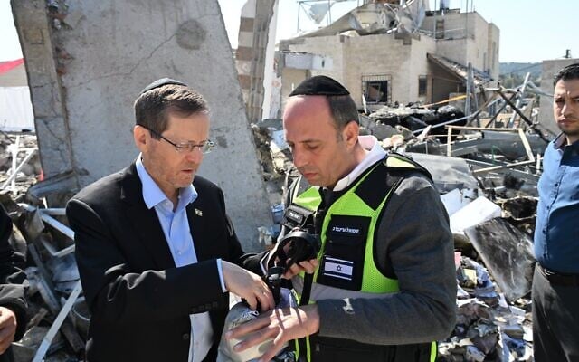Le président Isaac Herzog (à gauche), aux côtés du maire de Beit Shemesh, Shmuel Greenberg, en visite sur le site d'une attaque de missiles iraniens à Beit Shemesh, qui a causé la mort de neuf civils, le 2 mars 2026. (Crédit : Haïm Zach/Bureau de la presse gouvernementale)