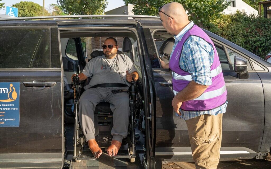 Un bénévole de la Purple Vest Mission aidant un homme en situation de handicap à rejoindre un lieu sûr pendant l'Opération "Lion rugissant". (Crédit : Autorisation)