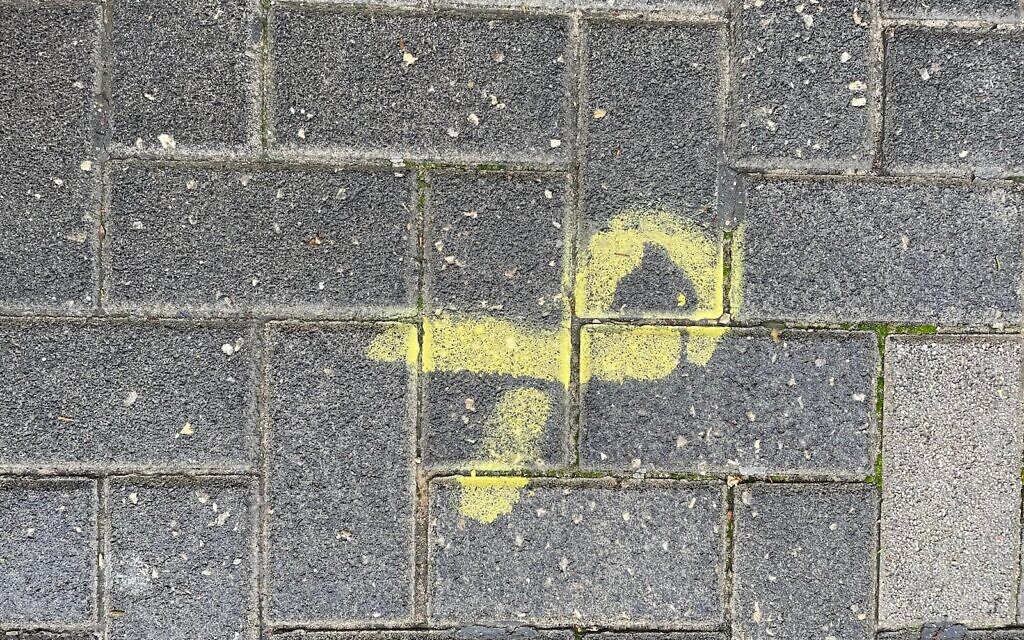 Un ruban jaune, symbole de l'attente du retour des otages, tagué sur un trottoir. (Crédit : Times of Israel) Un ruban jaune, symbole de l'attente du retour des otages, tagué sur un trottoir. (Crédit : Times of Israel)
