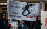Des manifestants brandissent une banderole appelant à l'arrêt des exécutions en Iran lors d'un rassemblement à Berlin, en Allemagne, le 10 janvier 2026, en soutien aux manifestations en Iran. (Crédit: John MacDougall / AFP)