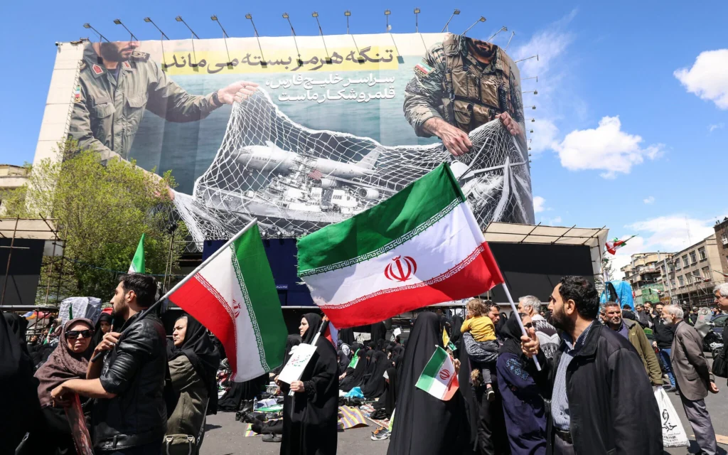 Des Iraniens brandissant des drapeaux de la République islamique d'Iran sous un grand panneau d'affichage indiquant « Le détroit d'Ormuz reste fermé », alors que la foule se rassemble sur la place de la Révolution à Téhéran après que les États-Unis et l'Iran se sont mis d'accord sur un cessez-le-feu de deux semaines, le 8 avril 2026. (Crédit : Atta Kenare/AFP) Des Iraniens brandissant des drapeaux de la République islamique d'Iran sous un grand panneau d'affichage indiquant « Le détroit d'Ormuz reste fermé », alors que la foule se rassemble sur la place de la Révolution à Téhéran après que les États-Unis et l'Iran se sont mis d'accord sur un cessez-le-feu de deux semaines, le 8 avril 2026. (Crédit : Atta Kenare/AFP)
