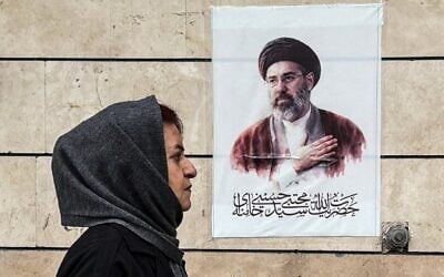 Une Iranienne passant devant une affiche représentant le portrait de Mojtaba Khamenei, le nouveau guide suprême de l'Iran, dans la capitale Téhéran, le 13 avril 2026 (Crédit : Atta Kenare/AFP)