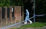 Un expert de la police travaillant à l'intérieur d'un périmètre de sécurité mis en place près de la Kenton United Synagogue, lieu d'un incendie criminel survenu pendant la nuità Harrow, au nord-ouest de Londres, le 19 avril 2026. (Crédit : Justin Tallis/AFP)