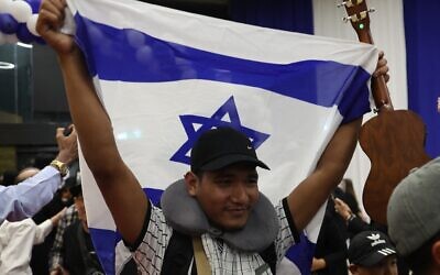 Un membre de la communauté des Bnei Menashe en Inde brandit un drapeau israélien à son arrivée à l'aéroport Ben Gurion, le 23 avril 2026. (Crédit : Jack Guez/AFP)