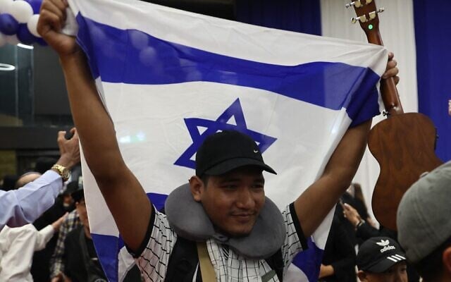 Un membre de la communauté des Bnei Menashe en Inde brandit un drapeau israélien à son arrivée à l'aéroport Ben Gurion, le 23 avril 2026. (Crédit : Jack Guez/AFP) Un membre de la communauté des Bnei Menashe en Inde brandit un drapeau israélien à son arrivée à l'aéroport Ben Gurion, le 23 avril 2026. (Crédit : Jack Guez/AFP)