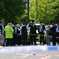 Des habitants observent depuis l’extérieur d’une zone bouclée à la suite d’une attaque à l’arme blanche dans le quartier de Golders Green, au nord de Londres, le 29 avril 2026 (Crédit: JUSTIN TALLIS / AFP)