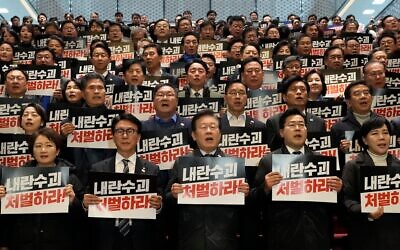 Lee Jae Myung, chef du Parti des Démocrates, principal parti d'opposition sud-coréen (au centre en bas), scandant des slogans lors d'une conférence de presse avec les membres de son parti à l'Assemblée nationale à Séoul, en Corée du Sud, le 7 décembre 2024. Les pancartes portent l'inscription « Punissez le chef de la rébellion ». (Crédit : Ahn Young-joon/AP)