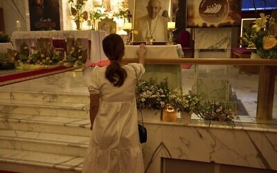 Illustration : Une femme touchant un portrait du pape François à l'intérieur de l'église catholique Saint-François-d'Assise à Jebel Ali, à Dubaï, aux Émirats arabes unis, le 21 avril 2025. (Crédit : Fatima Shbair/AP)