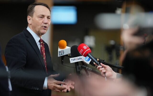 Le ministre polonais des Affaires étrangères, Radoslaw Sikorski, s'adressant aux médias à son arrivée à une réunion des ministres des Affaires étrangères de l'UE, au siège du Conseil européen, à Bruxelles, en Belgique, le 16 mars 2026. (Crédit : /AP/Virginia Mayo)