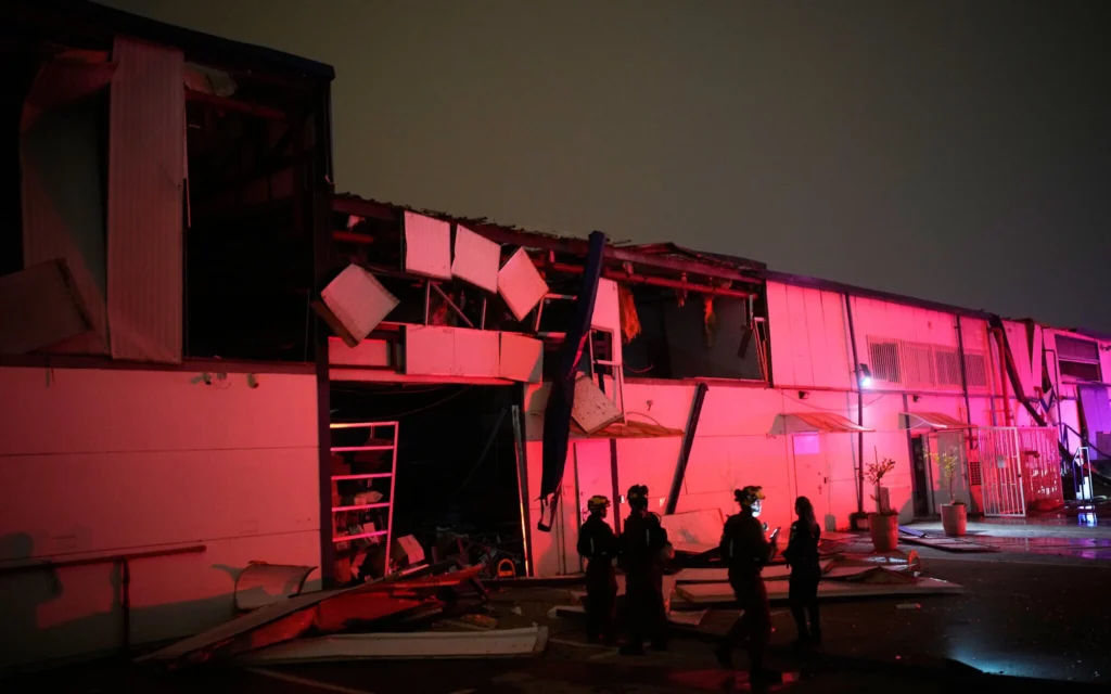 Des forces de sécurité israéliennes et des équipes de secours inspectent un site touché par un missile iranien à Petah Tikva, le 2 avril 2026. (Crédit : AP/Ohad Zwigenberg)