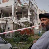 Un homme se tient devant une maison touchée par un missile à fragmentation iranien à Ramat Gan, le 4 avril 2026. (Crédit : Maya Levin/AP)