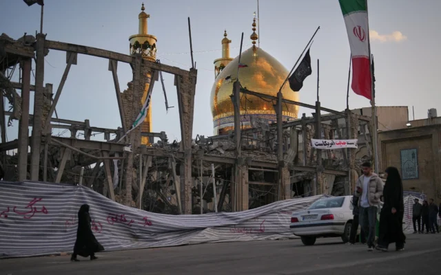 Des piétons passent devant un bâtiment détruit dans l'enceinte du Grand Hosseiniyeh, avec la mosquée visible en arrière-plan, qui, selon les responsables présents sur place, a été touchée par des frappes aériennes américano-israéliennes à Zanjan, en Iran, le 4 avril 2026. (Crédit: AP Photo/Francisco Seco)