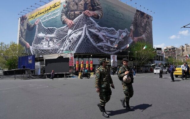 Deux policiers marchant devant un panneau d'affichage représentant des avions et des navires américains et israéliens pris dans un filet de pêche des forces armées iraniennes, avec des inscriptions en farsi : « Le détroit d'Ormuz restera fermé, tout le golfe Persique est notre terrain de chasse », sur la place de la Révolution islamique, à Téhéran, en Iran, le 5 avril 2026 (Crédit : Vahid Salemi/AP Photo) Deux policiers marchant devant un panneau d'affichage représentant des avions et des navires américains et israéliens pris dans un filet de pêche des forces armées iraniennes, avec des inscriptions en farsi : « Le détroit d'Ormuz restera fermé, tout le golfe Persique est notre terrain de chasse », sur la place de la Révolution islamique, à Téhéran, en Iran, le 5 avril 2026 (Crédit : Vahid Salemi/AP Photo)