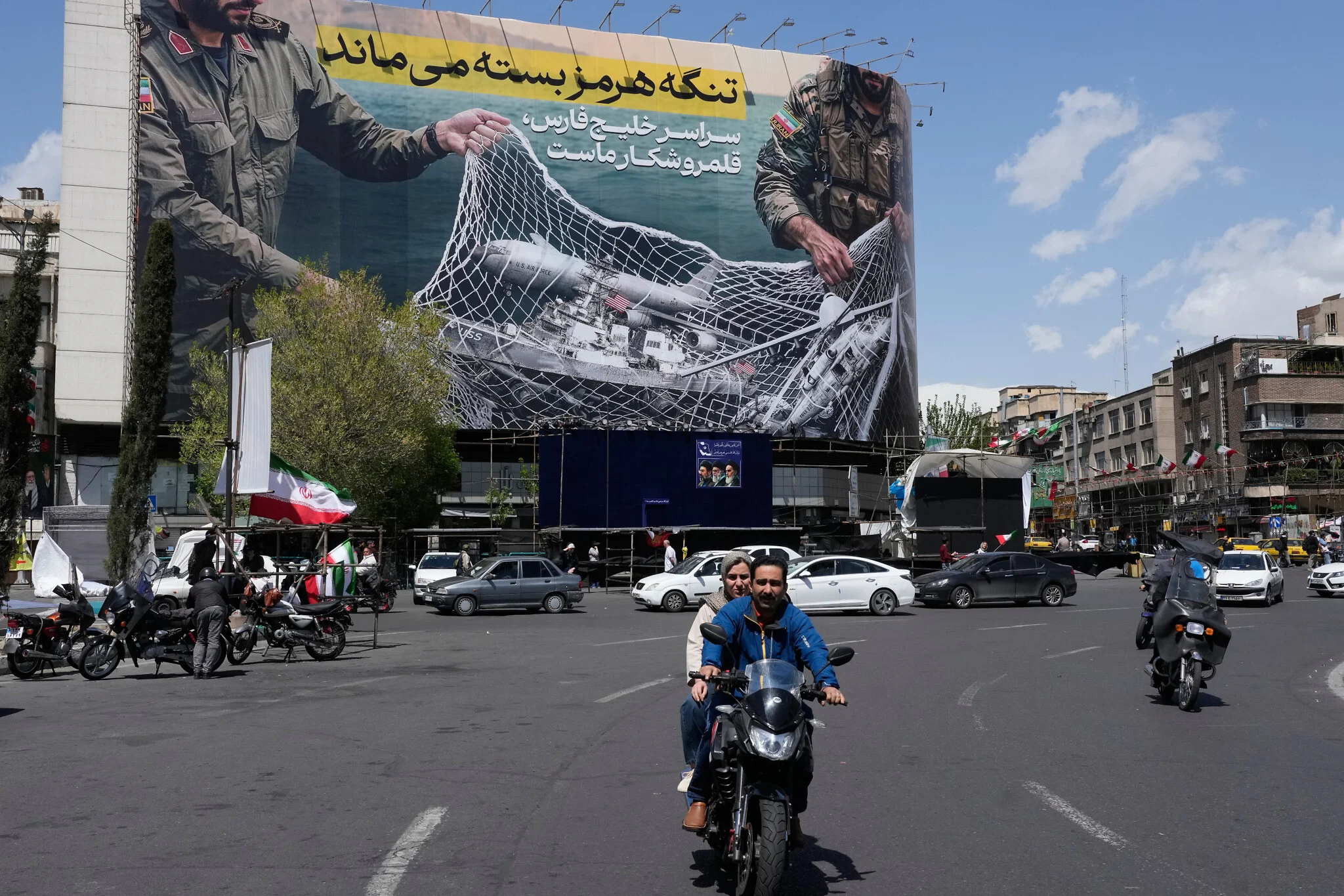 Des véhicules et des motos passent devant un panneau anti-américain représentant un avion américain entrant dans un filet de pêche des forces armées iraniennes, avec des inscriptions en farsi : « Le détroit d’Ormuz restera fermé, tout le golfe Persique est notre terrain de chasse », sur la place de la Révolution islamique, dans le centre-ville de Téhéran, en Iran, le 5 avril 2026. (Crédit: AP Photo/Vahid Salemi) Des véhicules et des motos passent devant un panneau anti-américain représentant un avion américain entrant dans un filet de pêche des forces armées iraniennes, avec des inscriptions en farsi : « Le détroit d’Ormuz restera fermé, tout le golfe Persique est notre terrain de chasse », sur la place de la Révolution islamique, dans le centre-ville de Téhéran, en Iran, le 5 avril 2026. (Crédit: AP Photo/Vahid Salemi)