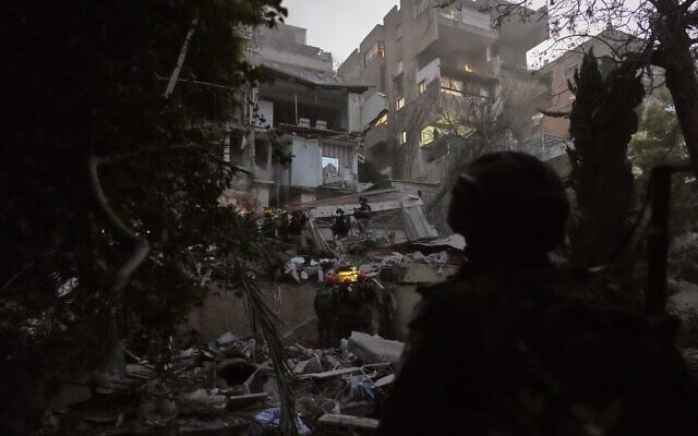 Les forces de sécurité et les équipes de secours israéliennes interviennent au milieu des décombres d'un immeuble résidentiel touché par un missile iranien à Haïfa, le 5 avril 2026. (Crédit : AP Photo/Ariel Schalit)