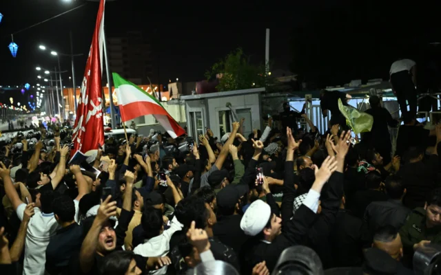 Un groupe de manifestants irakiens prend d'assaut le consulat du Koweït et retire le drapeau national koweïtien du bâtiment, à Bassorah, en Irak, le 8 avril 2026. (Crédit : Ali Rahim/AP)