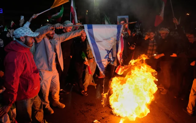 Des manifestants pro-gouvernementaux iraniens brûlent les drapeaux américain et israélien lors d’un rassemblement organisé après l’annonce d’un cessez-le-feu de deux semaines dans la guerre contre les États-Unis et Israël, sur la place Enqelab-e-Eslami, ou place de la Révolution islamique, à Téhéran, en Iran, le mercredi 8 avril 2026. (Crédit : Vahid Salemi/AP)