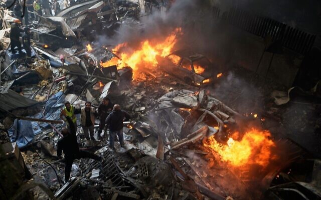 Secouristes et bénévoles fouillant les décombres à côté de voitures en feu sur le site d'une frappe aérienne israélienne ayant touché un immeuble d'habitation, à Beyrouth, au Liban, le 8 avril 2026. (Crédit : Bilal Hussein/AP)