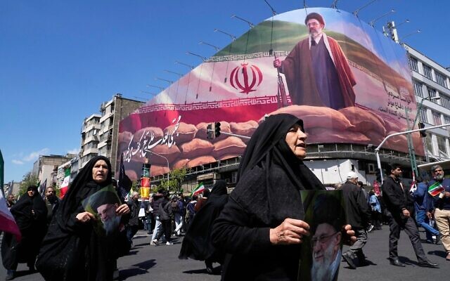Des femmes passant devant un panneau d'affichage représentant le guide suprême iranien Mojtaba Khamenei, alors que des partisans du gouvernement se rassemblent pour marquer le 40ᵉ jour depuis l’élimination de son père, à Téhéran, en Iran, le 9 avril 2026. (Crédit : Vahid Salemi/AP Photo)