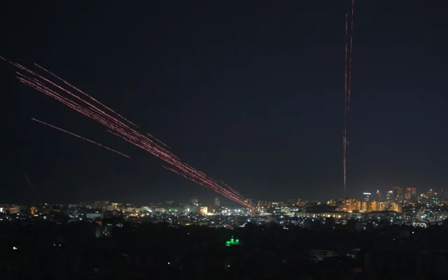 Des balles traçantes illuminent le ciel nocturne alors que des personnes tirent des balles réelles et des feux d'artifice en l'air à la suite d'un cessez-le-feu entre Israël et le Hezbollah, à Beyrouth, au Liban, tôt le 17 avril 2026. (Crédit: AP/Hassan Ammar)