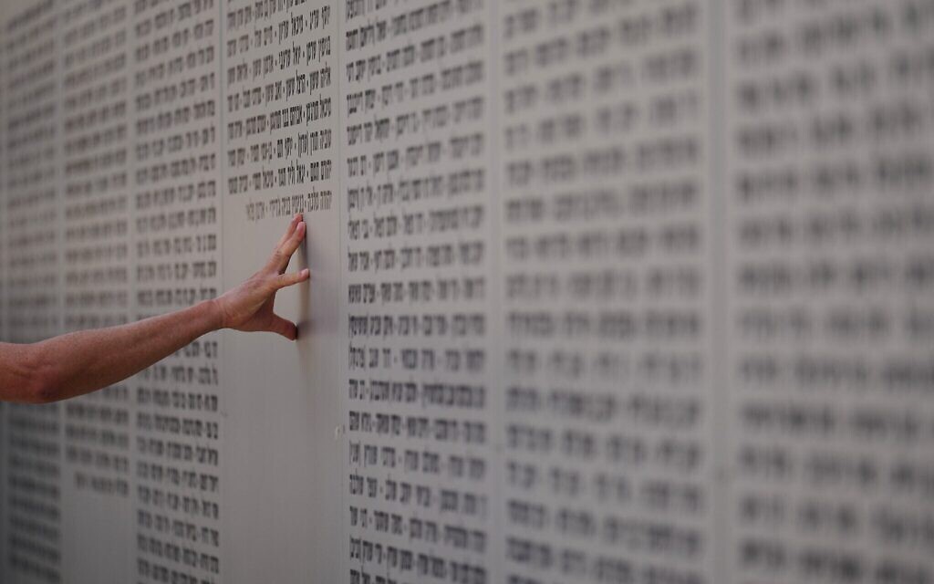 Un homme touchant le mur sur lequel sont inscrits les noms des soldats tombés au combat lors de Yom HaZikaron, au mémorial du Corps Blindé Mécanisé, à Latroun, en Israël, le 21 avril 2026. (Crédit : Ariel Schalit/AP Photo)