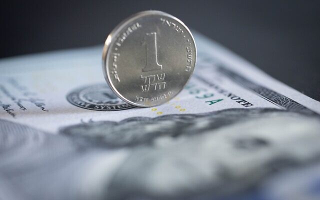 Illustration : Un shekel et un billet de 100 dollars, le 13 avril 2026. (Crédit : Nati Shohat/Flash90)