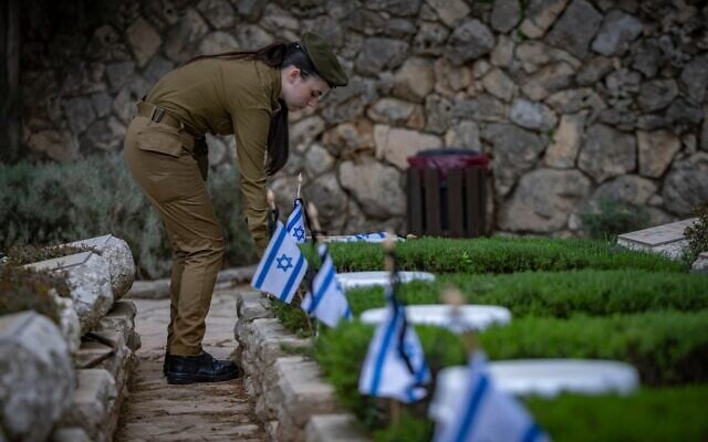 Des soldats de l'armée israélienne déposent des drapeaux israéliens sur les tombes de soldats lors de la cérémonie de dépôt de drapeaux au cimetière militaire du Mont Herzl à Jérusalem, le 19 avril 2026, à la veille deYom HaZikaron. (Crédit : Yonatan Sindel/Flash90)