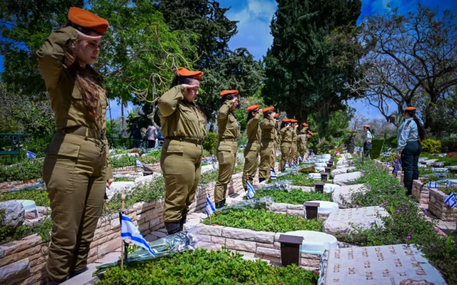 Des soldates de l'armée israélienne déposant des fleurs et des drapeaux d'Israël sur les tombes des soldats israéliens tombés au combat, au cimetière militaire de Kiryat Shaul, à la veille de Yom HaZikaron, le 20 avril 2026. (Crédit : Avshalom Sassoni/Flash90)