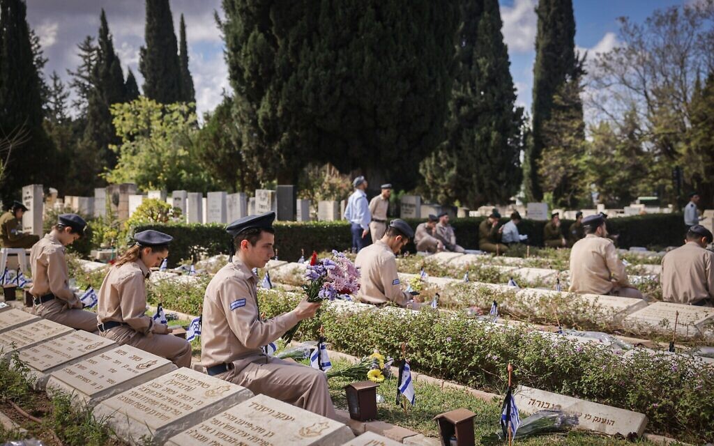 Des civils et des soldats israéliens se recueillant sur les tombes de soldats israéliens, au cimetière militaire de Nahalat Yitzhak, à Tel Aviv, à Yom HaZikaron, le 21 avril 2026. (Crédit : Miriam Alster/Flash90)