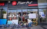 Des personnes se sont rassemblées devant un restaurant Pizza Hut à Petah Tikva, allumant des bougies et déposant des fleurs en mémoire de Yemanu Binyamin Zalka, un employé qui a été poignardé et est décédé des suites de ses blessures la veille de la fête de l'Indépendance, le 27 avril 2026. (Crédit : Avshalom Sassoni/Flash90)