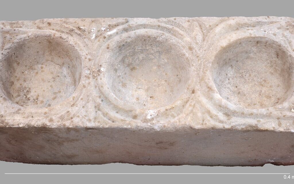Le bloc de marbre rectangulaire comportant trois cavités hémisphériques destinées à contenir de l'huile, mis au jour dans la nef sud de la cathédrale d'Hippone, à l'est du lac de Tibériade, lors d'une découverte annoncée en mars 2026. (Crédit : Michael Eisenberg/Université de Haïfa)
