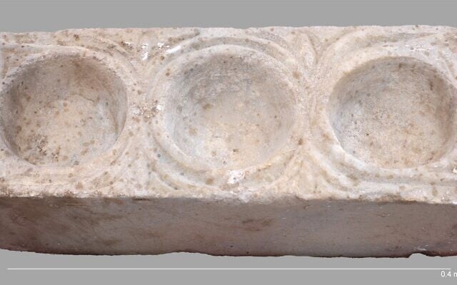 Le bloc de marbre rectangulaire comportant trois cavités hémisphériques destinées à contenir de l'huile, mis au jour dans la nef sud de la cathédrale d'Hippone, à l'est du lac de Tibériade, lors d'une découverte annoncée en mars 2026. (Crédit : Michael Eisenberg/Université de Haïfa)