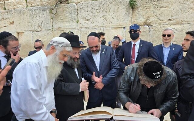 Le président argentin Javier Milei (à gauche) signant le livre d'or, aux côtés de son ambassadeur, le rabbin Shimon Axel Wahnish (au centre), et du rabbin du mur Occidental, Shmuel Rabinovitch, au mur Occidental, le 19 avril 2026. (Crédit : Autorisation)