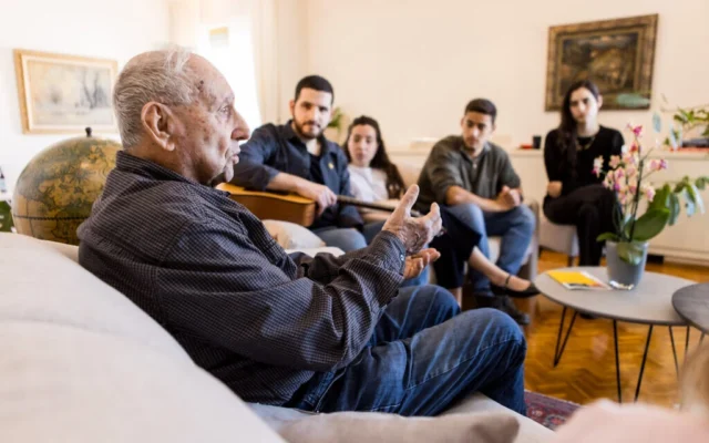 Le survivant de la Shoah Tommy Shaham témoigne lors d'une commémoration dans le salon du Zikaron BaSalon sur cette photo non datée. (Avec l'aimable autorisation de Zikaron BaSalon)