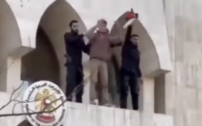 Un homme présenté par les médias arabes comme un agent de sécurité syrien (à droite) brandissant un drapeau "palestinien" qu'il a retiré  lors d'une manifestation anti-Israël du bâtiment de l'ambassade des Émirats arabes unis, à Damas, en Syrie, le 3 avril 2026. (Crédit : Capture d'écran/X ; utilisée conformément à l'article 27a de la loi sur le droit d'auteur)