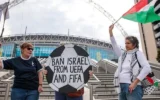 Des militants pro-palestiniens manifestent avec un panneau en forme de ballon de football et un drapeau palestinien devant le stade de Wembley pour exiger que la Fédération israélienne de football soit interdite de participation à l'UEFA et à la FIFA, le 2 octobre 2025 à Londres, au Royaume-Uni. (Mark Kerrison/En images via Getty Images via la JTA)