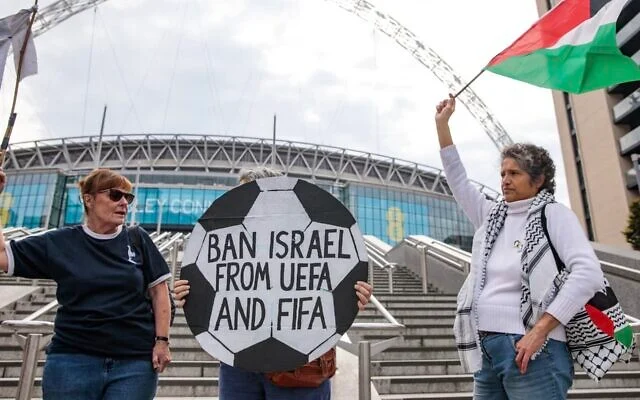 Des militants pro-palestiniens manifestent avec un panneau en forme de ballon de football et un drapeau palestinien devant le stade de Wembley pour exiger que la Fédération israélienne de football soit interdite de participation à l'UEFA et à la FIFA, le 2 octobre 2025 à Londres, au Royaume-Uni. (Mark Kerrison/En images via Getty Images via la JTA) Des militants pro-palestiniens manifestent avec un panneau en forme de ballon de football et un drapeau palestinien devant le stade de Wembley pour exiger que la Fédération israélienne de football soit interdite de participation à l'UEFA et à la FIFA, le 2 octobre 2025 à Londres, au Royaume-Uni. (Mark Kerrison/En images via Getty Images via la JTA)