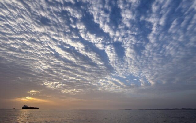 Le soleil se levant derrière un pétrolier ancré dans le détroit d'Ormuz, au large de l'île de Qeshm, en Iran, le 18 avril 2026. (Crédit : Asghar Besharati/AP)